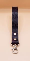 A dark purple leather strap with a silver metal clasp and hook attached to it.