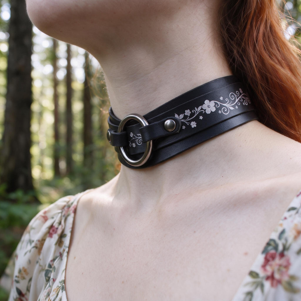 A close-up of a woman's neck wearing a black choker necklace with a floral design.
