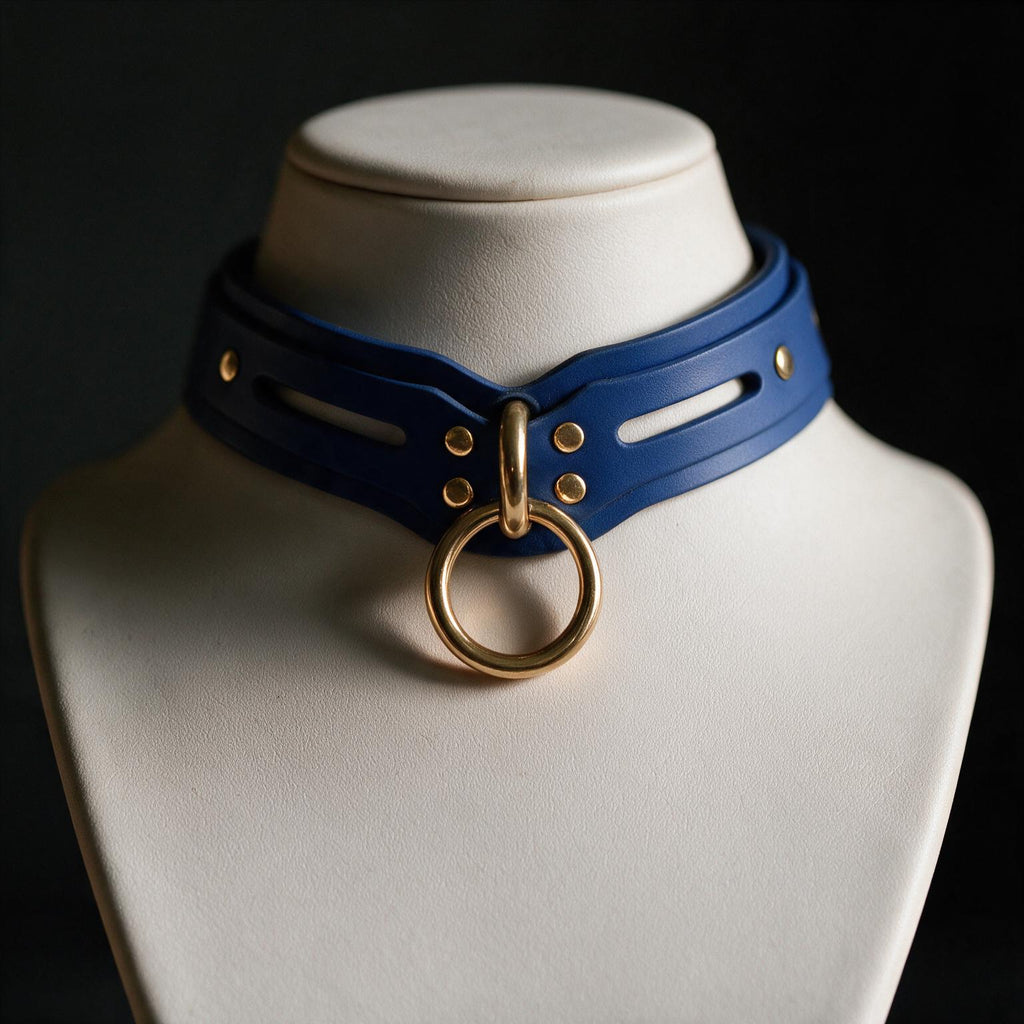A close-up view of a blue leather choker necklace with a gold ring and buckle, displayed on a white bust form against a dark background.