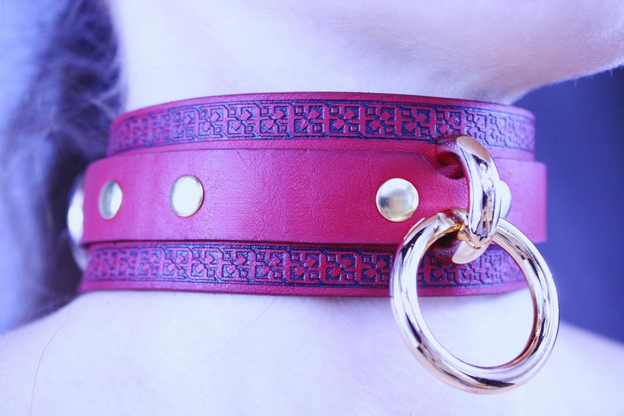 Bold red leather BDSM collar with O-ring and gold-tone hardware, featuring an embossed geometric design for submissive style.