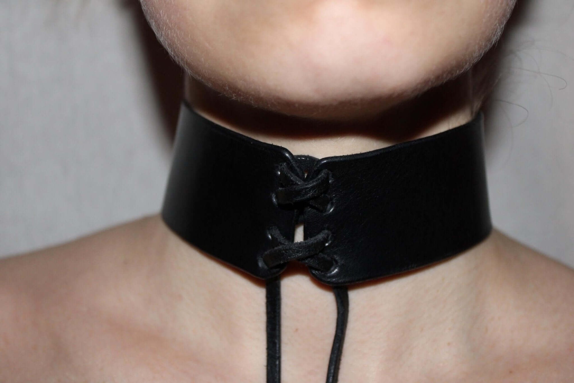 Unisex minimalist leather bondage choker collar for BDSM roleplay and intimacy, featuring a sleek design and lace-up detail.