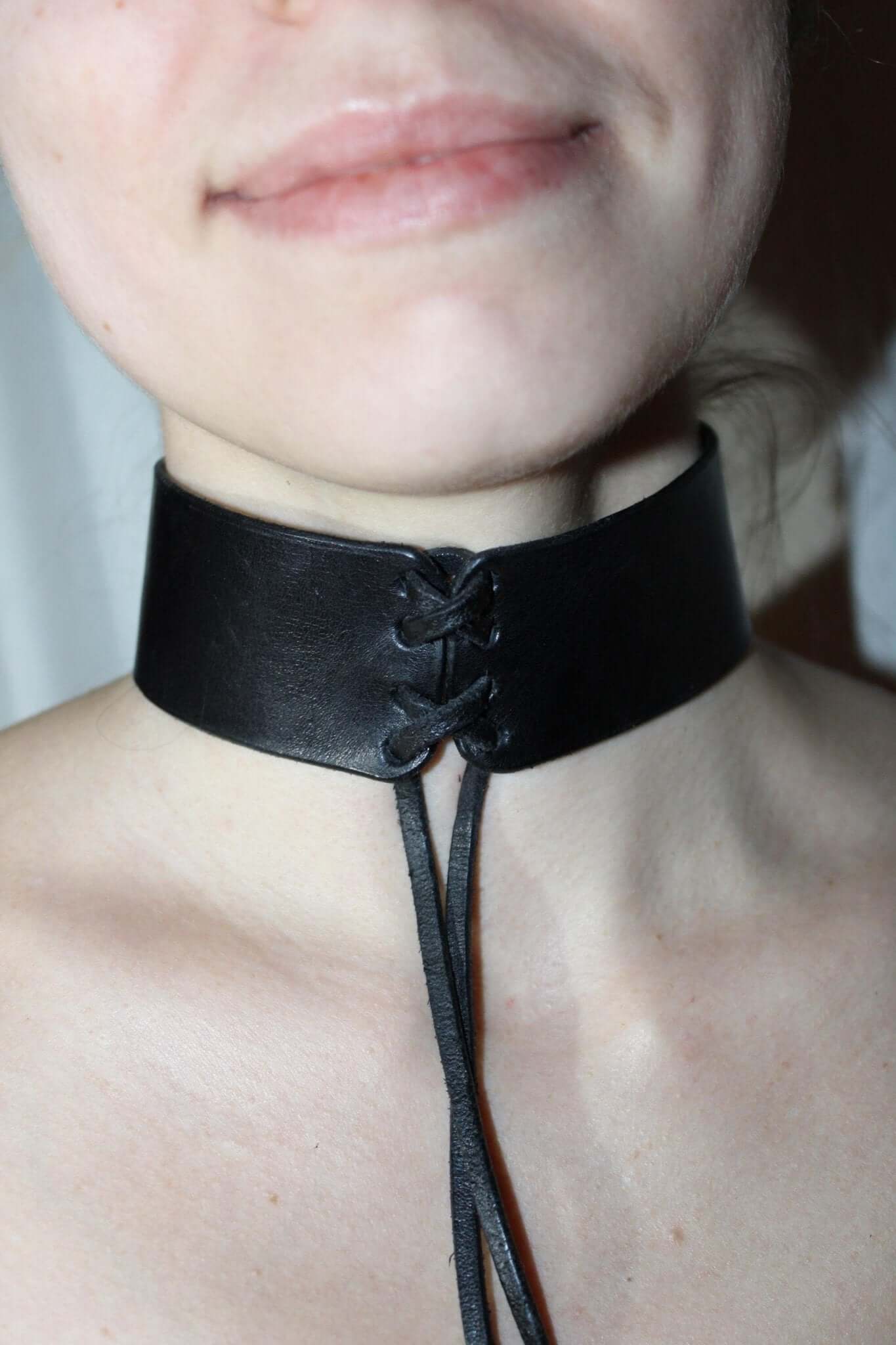 Black leather bondage choker, minimalist BDSM collar with lace-up detail, perfect for roleplay and fetish wear.