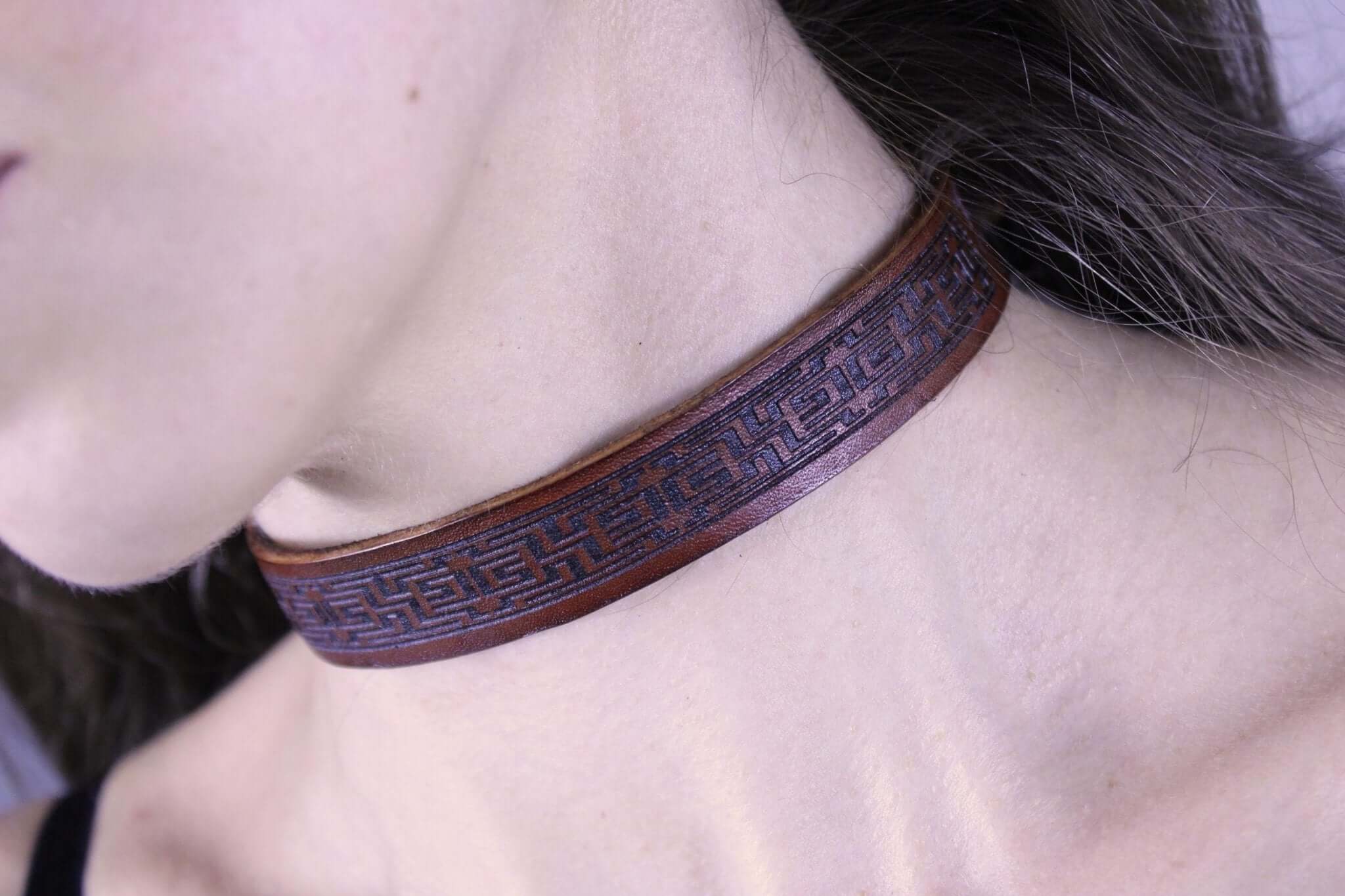 Brown leather submissive collar featuring intricate design, perfect for discreet day wear and BDSM jewelry.