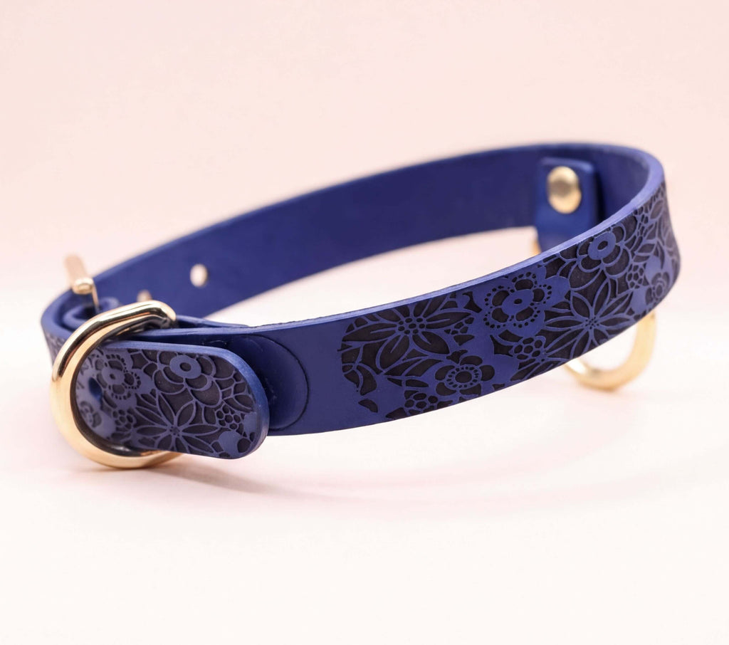 A blue leather dog collar with a floral pattern on it.