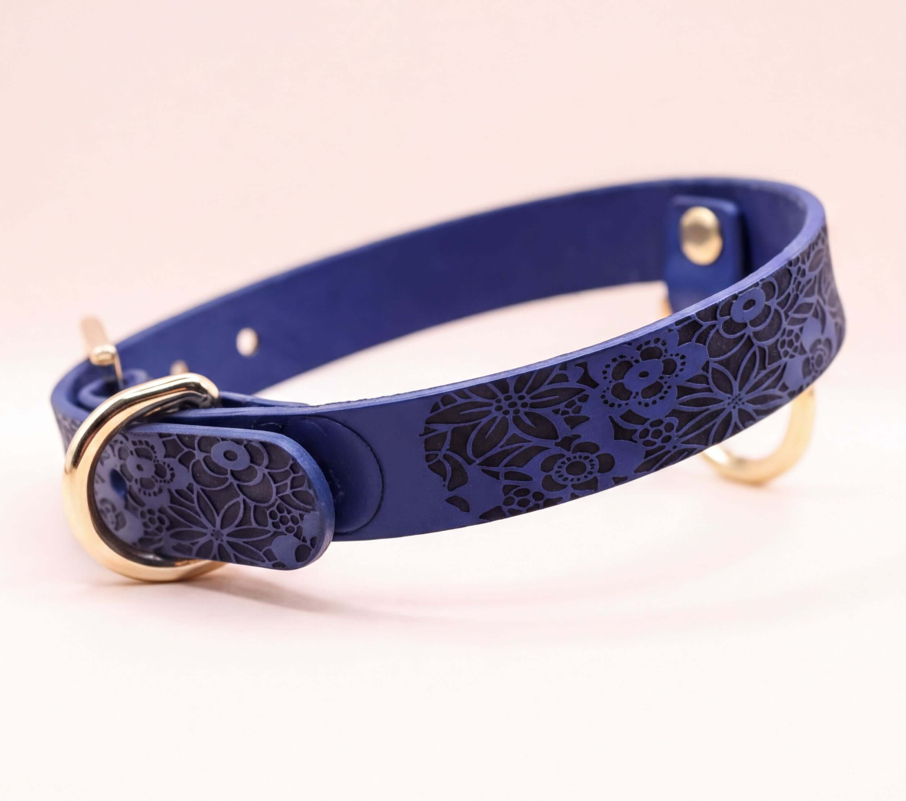 A blue leather dog collar with a floral pattern on it.