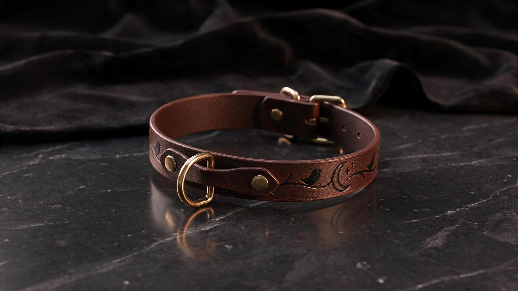 A brown leather collar with a decorative design on it, resting on a dark surface.