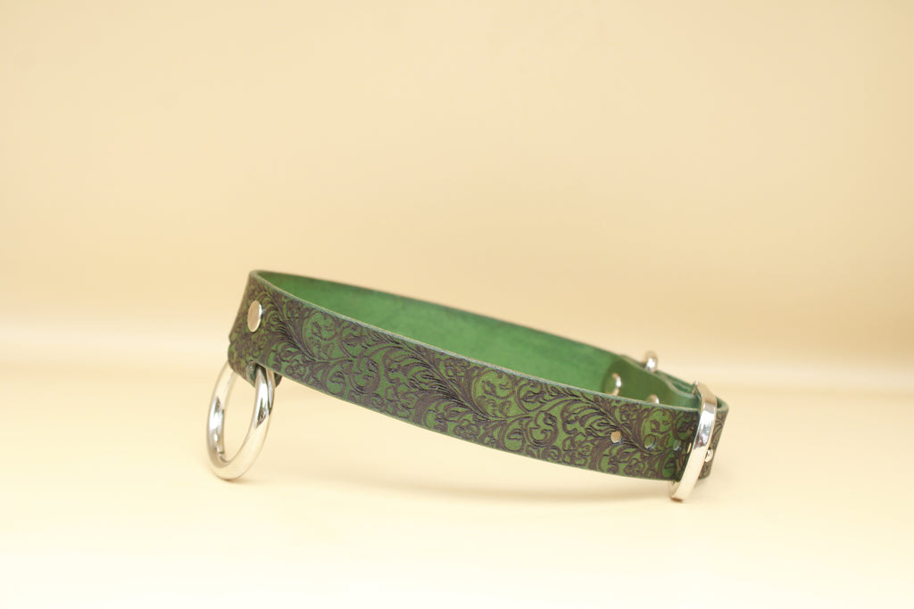 A green leather collar with a floral pattern and metal rings on the sides.