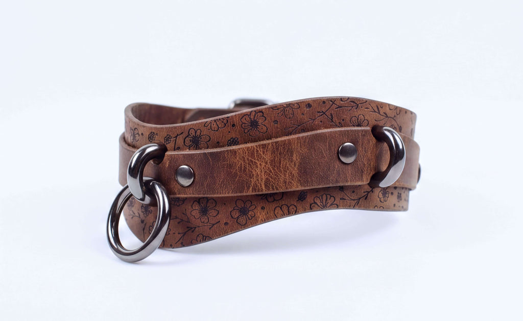 A brown leather choker necklace with metal rings and a metal clasp.