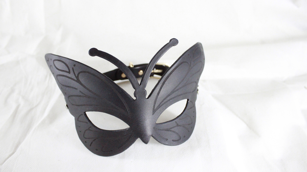 A black butterfly-shaped mask is displayed on a white background.