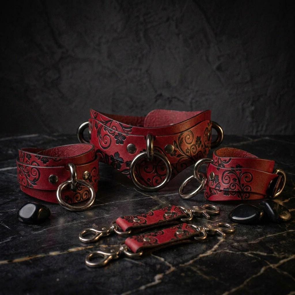 A set of red leather choker necklaces with black floral designs, arranged on a dark surface.