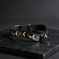 A black leather collar with a moon and star pattern design, featuring a metal ring with a clasp.