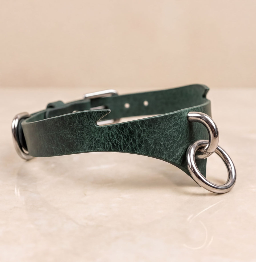 A green leather choker necklace with metal rings and a metal buckle.