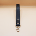 A black leather strap with a metal clasp and hook attached to it.