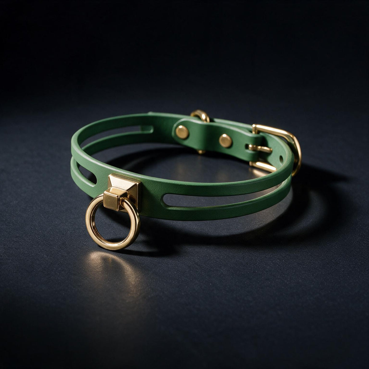 A green leather collar with a gold-colored buckle and ring is displayed against a dark background.