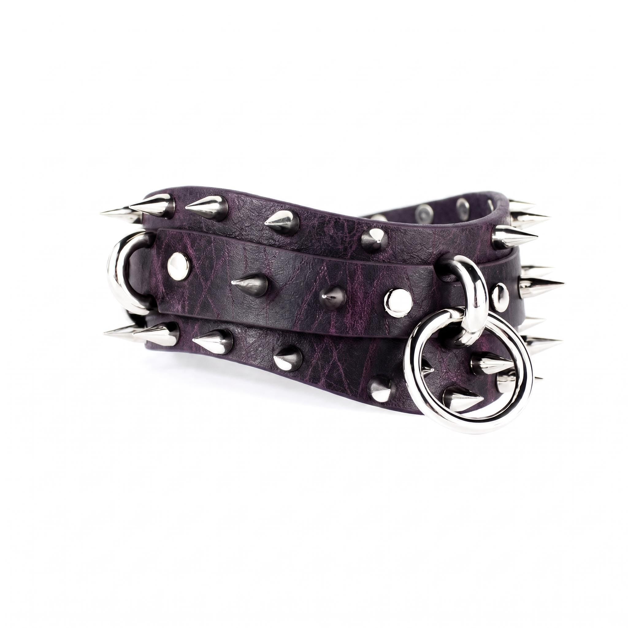 A purple leather belt with spikes and a metal ring attached to it.
