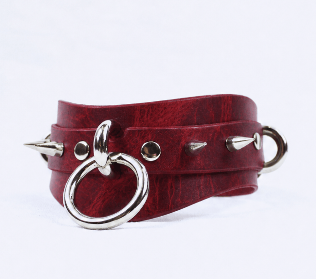 A red leather choker necklace with silver metal spikes protruding from it.