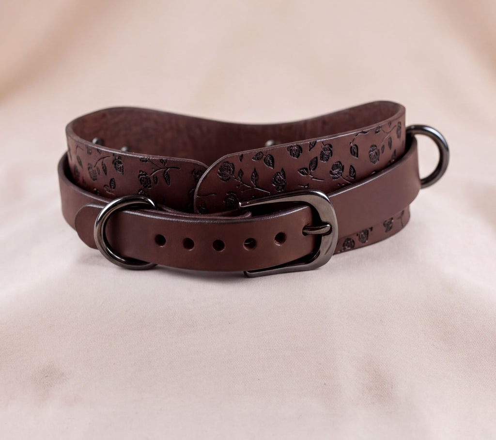 A brown leather belt with a floral pattern and metal buckle.