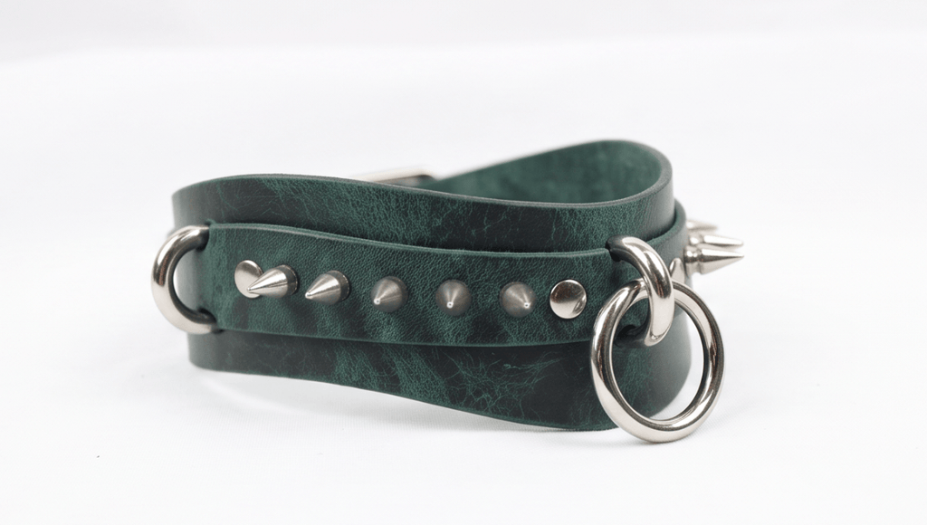 A green leather choker necklace with metal spikes and a metal ring.