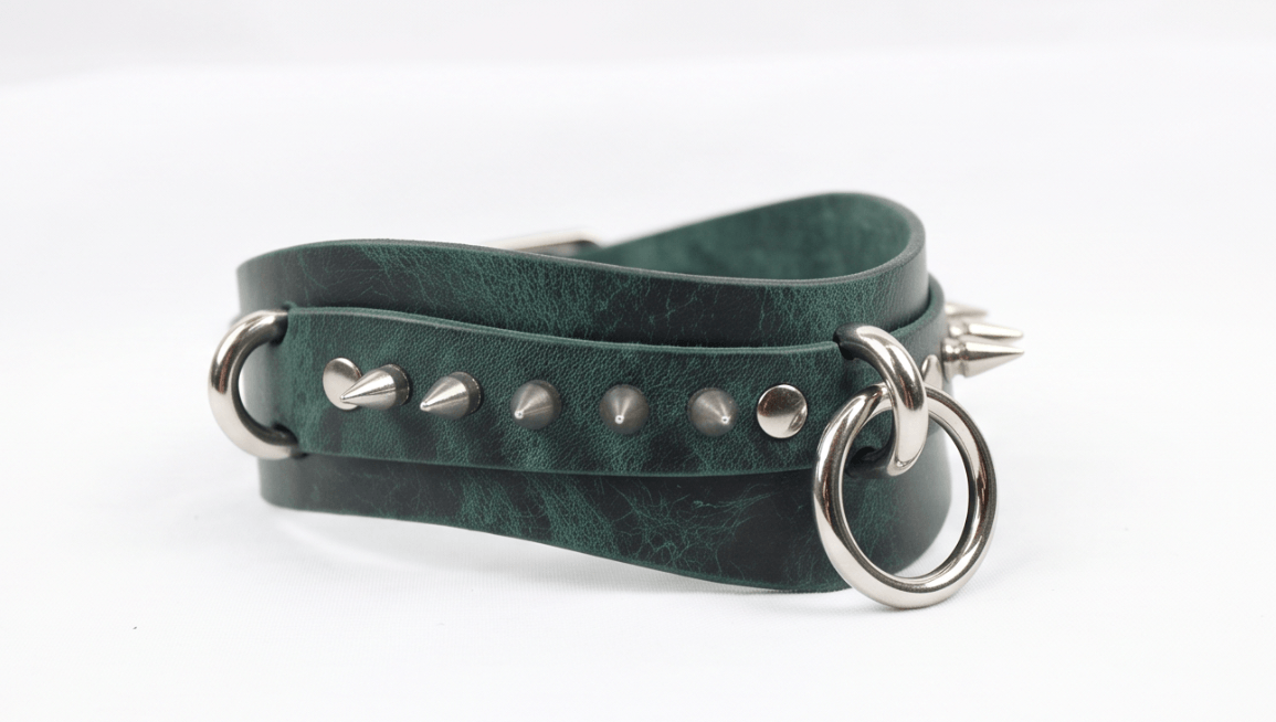 A green leather choker necklace with metal spikes and a metal ring.