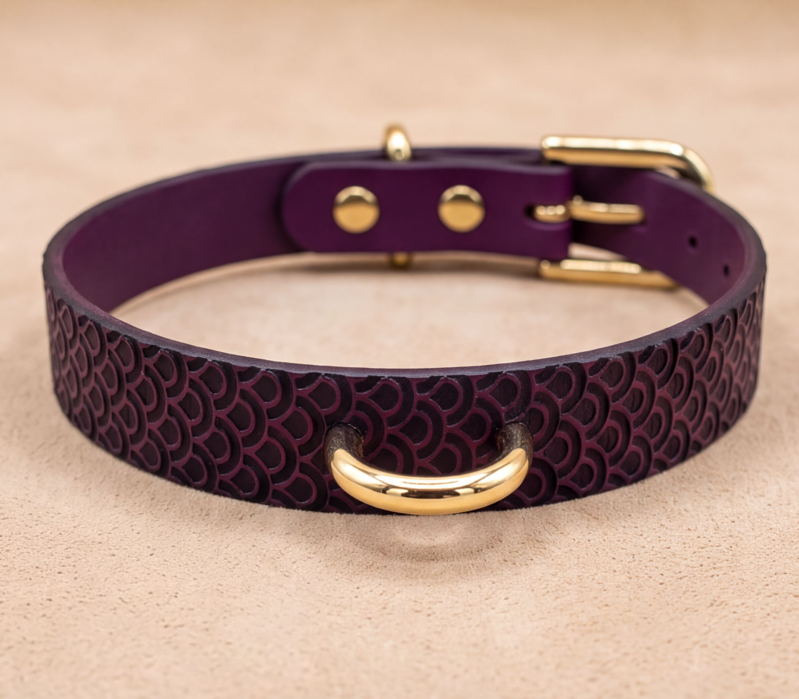 A purple leather dog collar with a gold-colored metal buckle.
