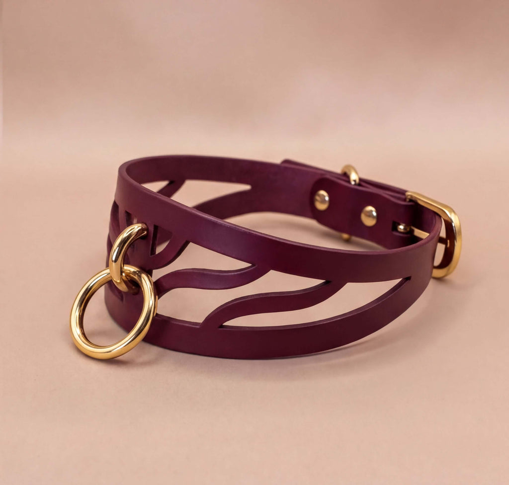 A burgundy leather choker necklace with a gold-colored metal ring and buckle.