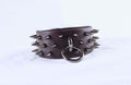 A leather bracelet with spikes protruding from it, and a metal ring attached to the bracelet.