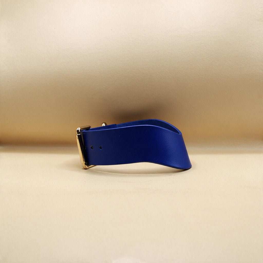 A blue leather belt with a gold buckle is shown against a beige background.