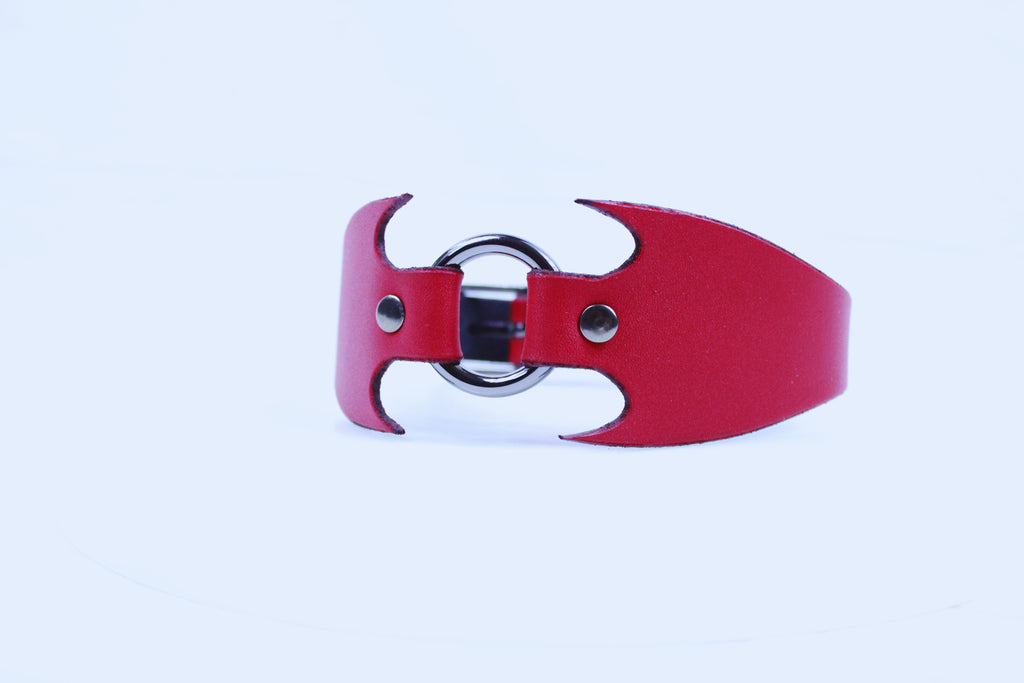 A red leather cuff with a metal ring and two metal buttons.