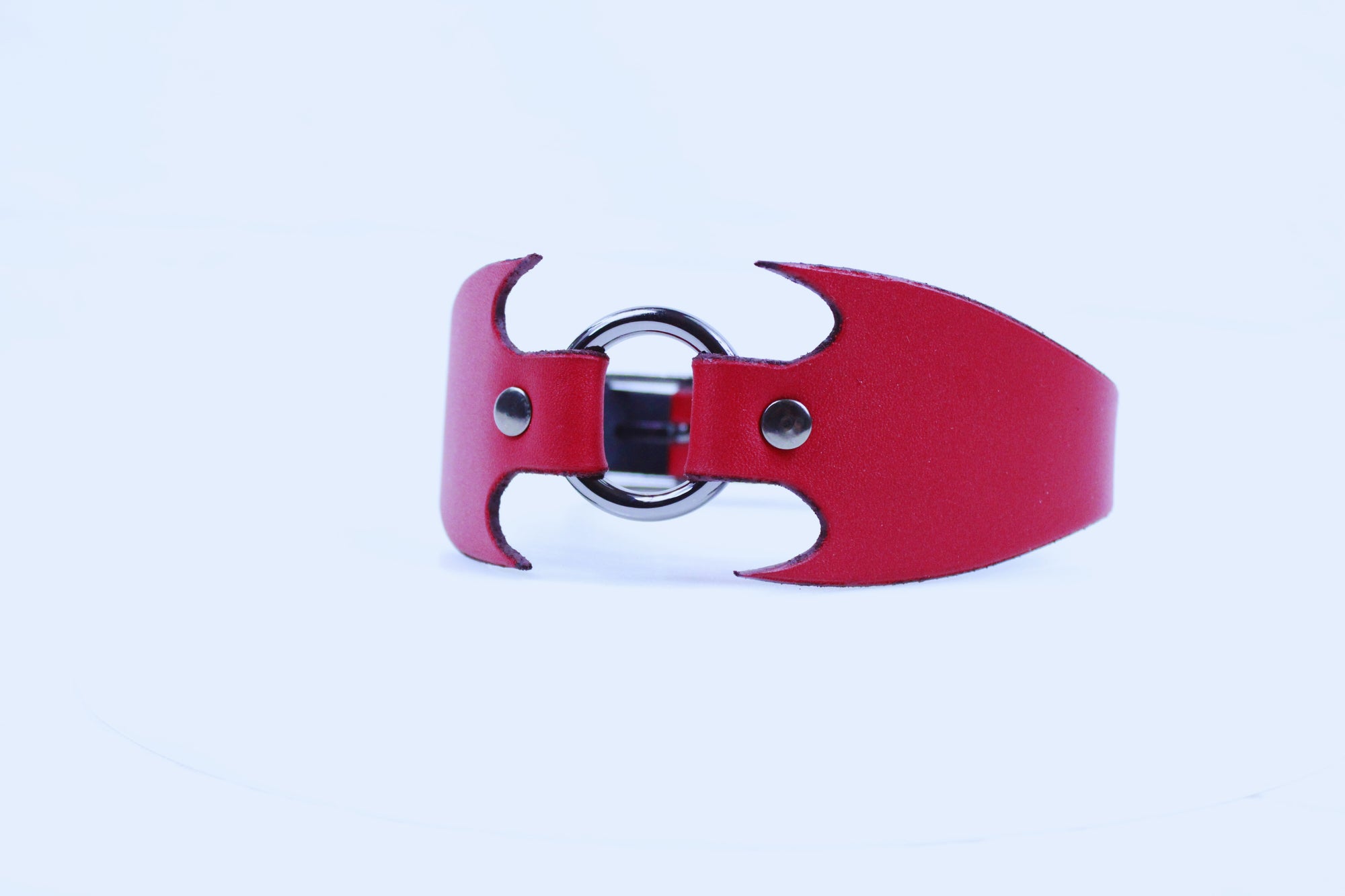 A red leather cuff with a metal ring and two metal buttons.