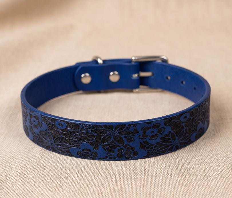 A blue dog collar with a floral pattern on it.