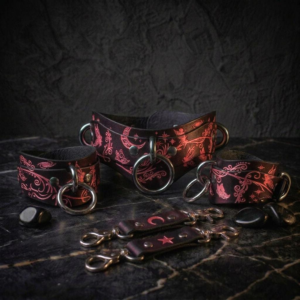 a collection of leather straps and charms, including a corset-style collar and various accessories, all displayed on a dark surface.