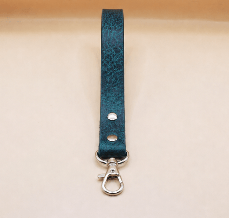 A dark green leather strap with a metal clasp and hook attached to it.