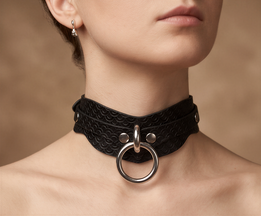 A close-up of a woman's neck and chest area, featuring a black leather choker necklace with a large metal ring.
