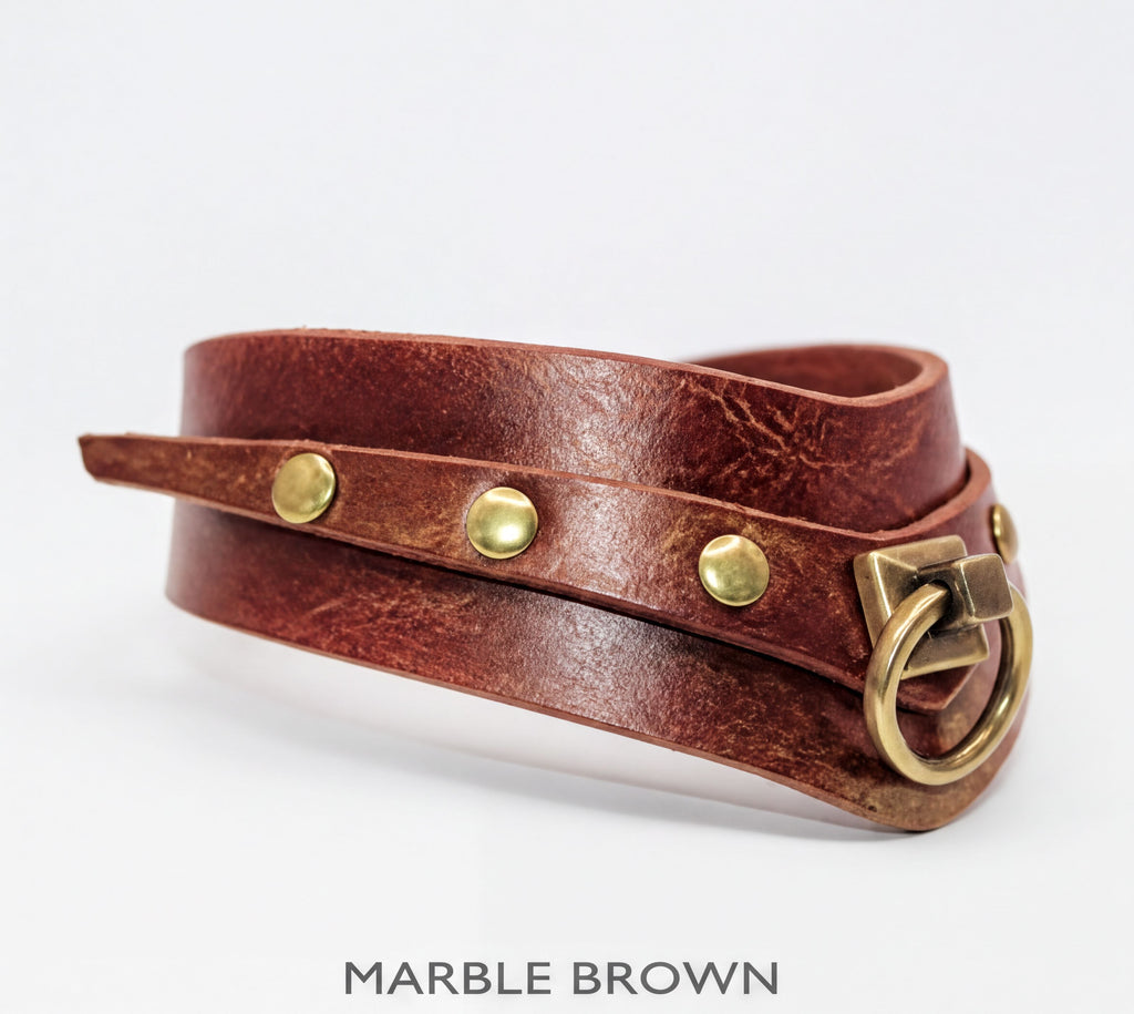 A brown leather choker necklace with brass hardware and three brass studs.
