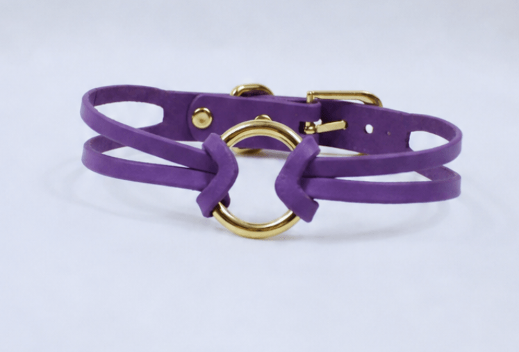 A purple leather choker necklace with a gold-colored circular clasp.