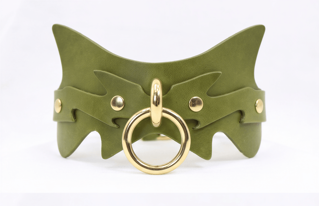 A green leather choker necklace with a gold-colored metal ring and two gold-colored metal studs on the sides.
