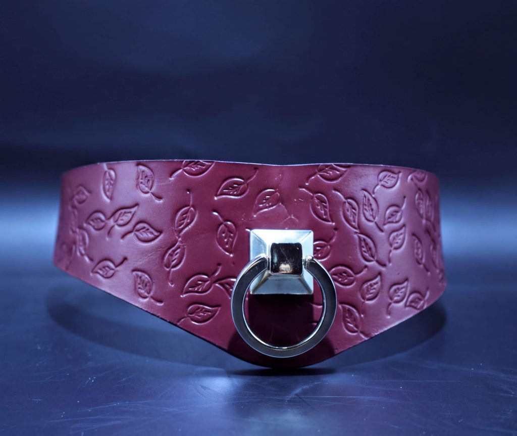 A burgundy leather choker necklace with a leaf-shaped metal ring and a silver metal clasp.