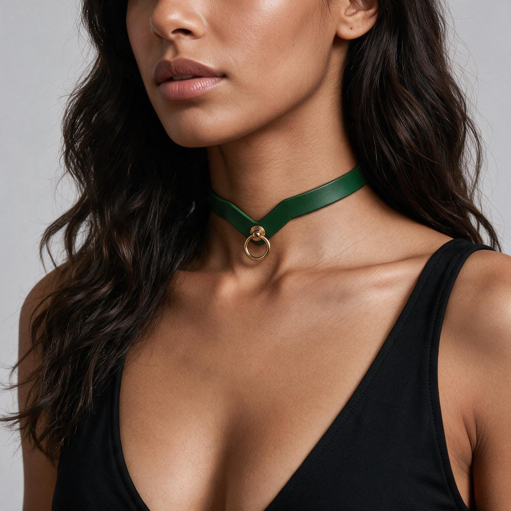 A close-up of a woman wearing a green choker necklace with a gold ring.