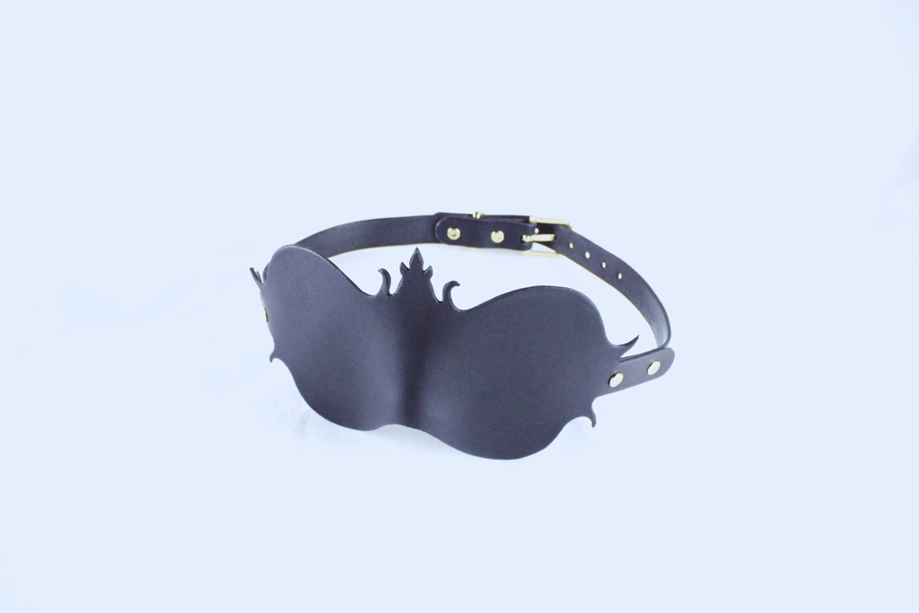 A black leather mask with a decorative design on the strap and a gold buckle.