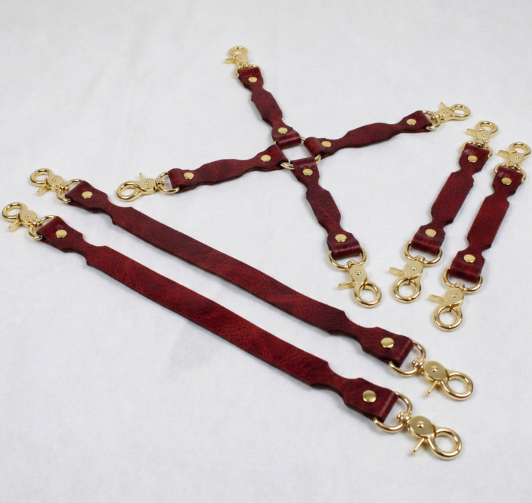 a collection of red leather straps with gold metal clasps, arranged in a way that they appear to be connected or linked together.