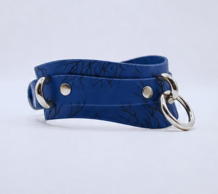 A blue leather choker necklace with a silver metal ring and two metal rings on either side.