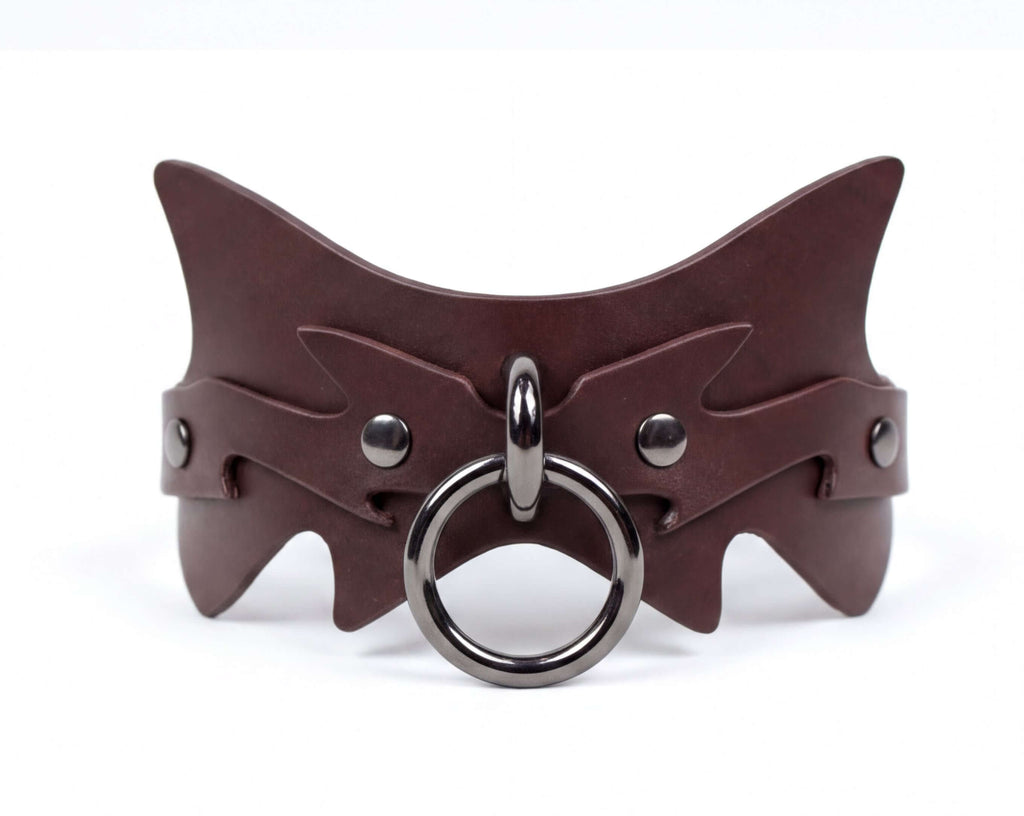 A brown leather choker necklace with a metal ring and a circular metal piece.