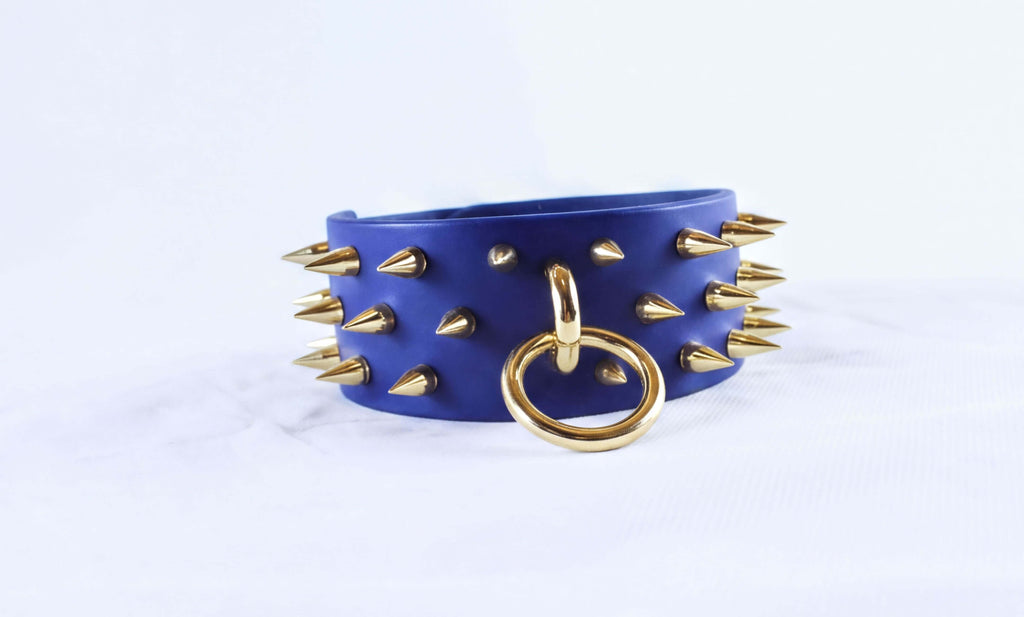 A blue leather choker necklace with gold spikes and a gold ring.