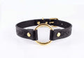 A black leather choker collar with a gold-colored circular buckle.