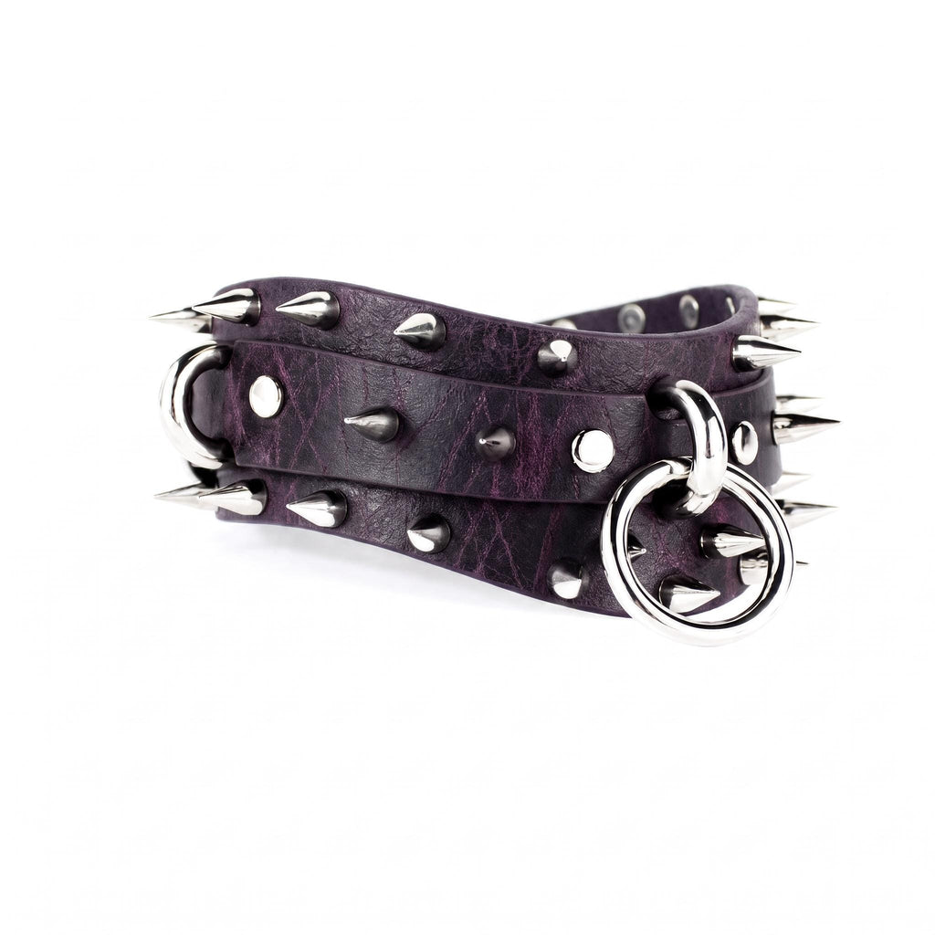 A purple leather belt with spikes and a metal ring attached to it.