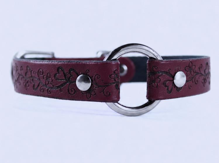 A burgundy leather collar with a circular metal buckle and floral designs.