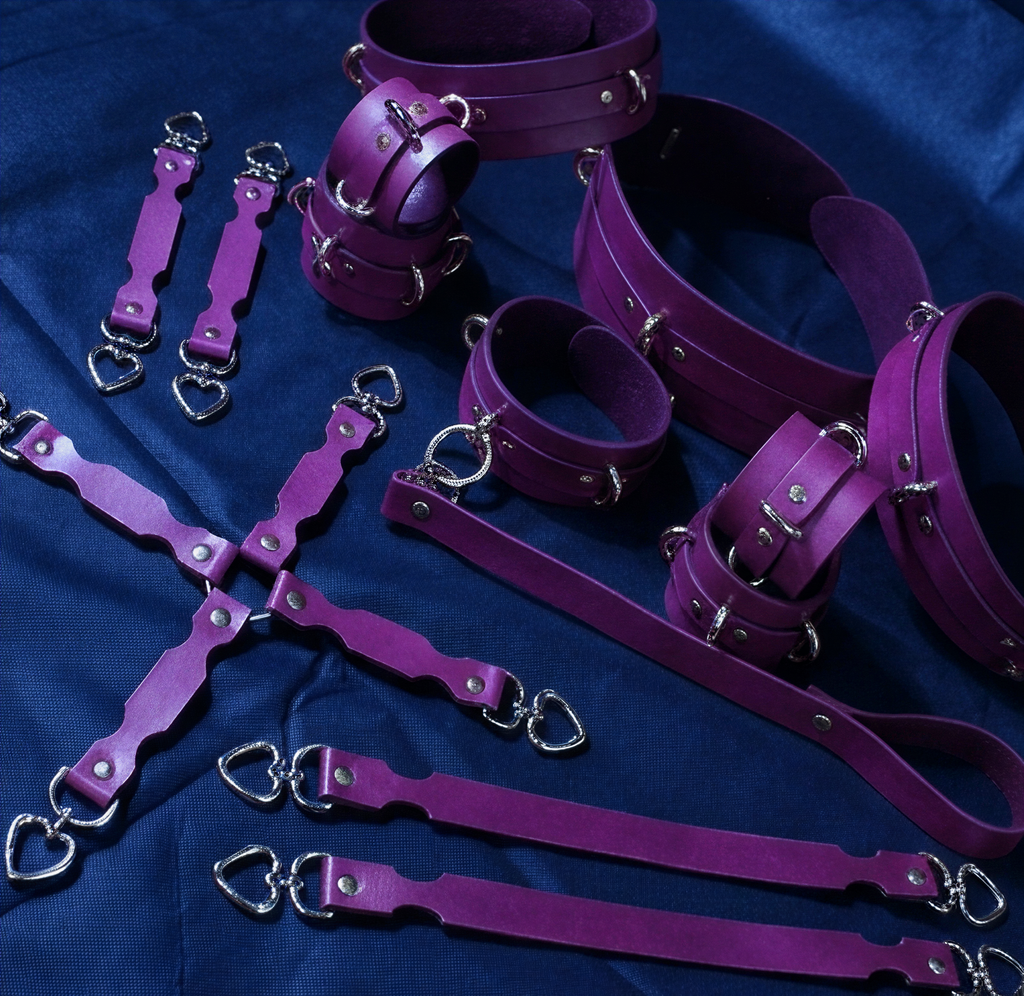 a collection of purple leather straps and restraints arranged on a blue background.