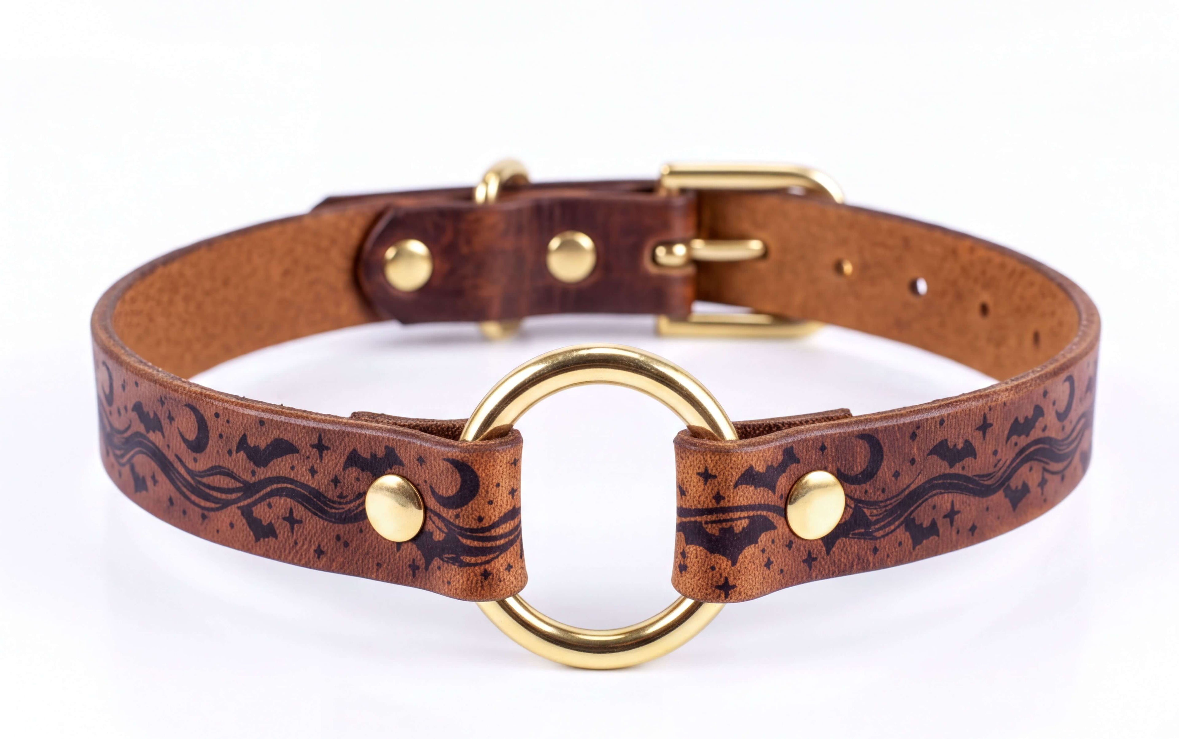 A brown leather collar with a gold-colored buckle and a circular ring design featuring stars and bats.
