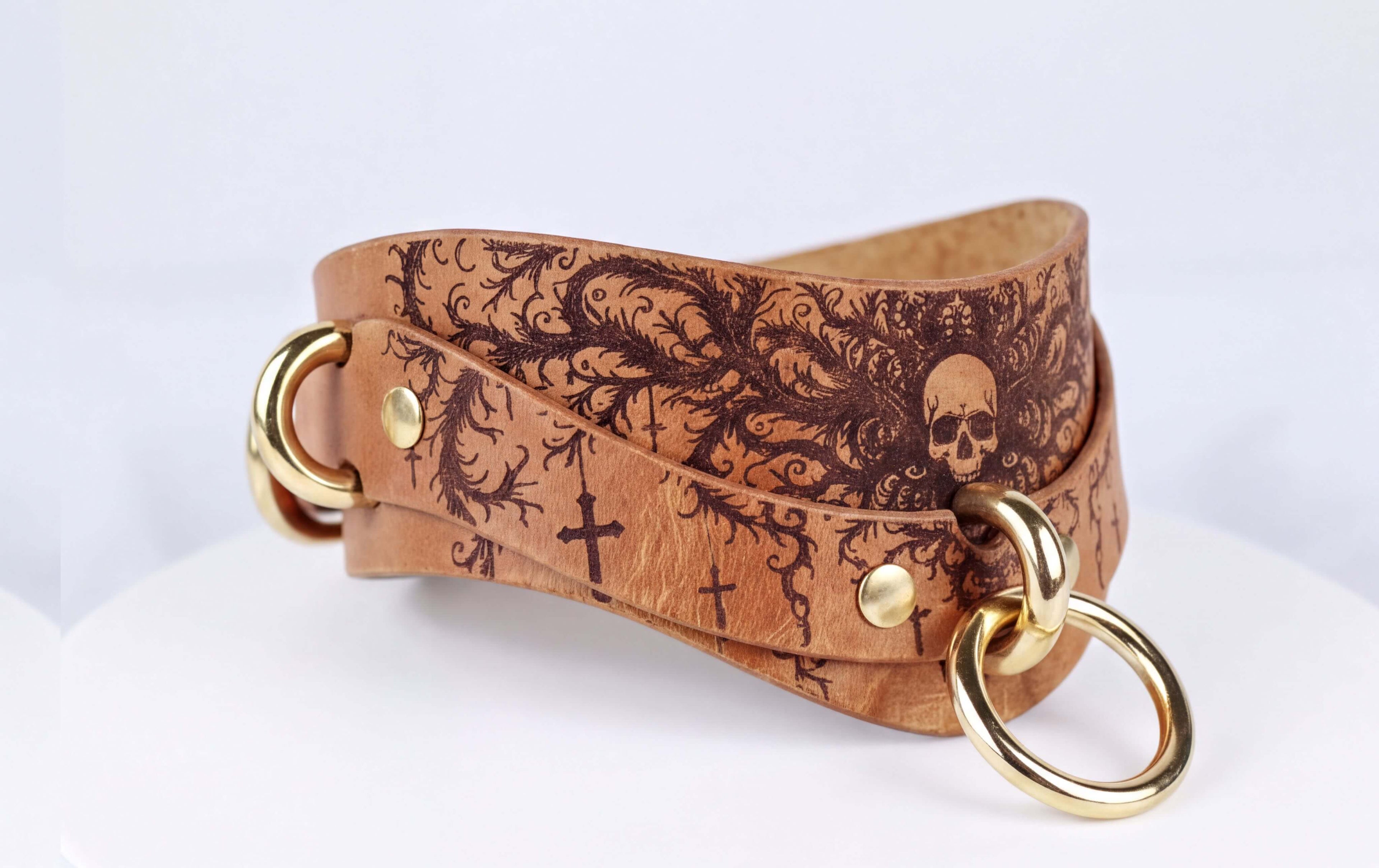 A leather bracelet with a skull design and gold-colored metal rings.