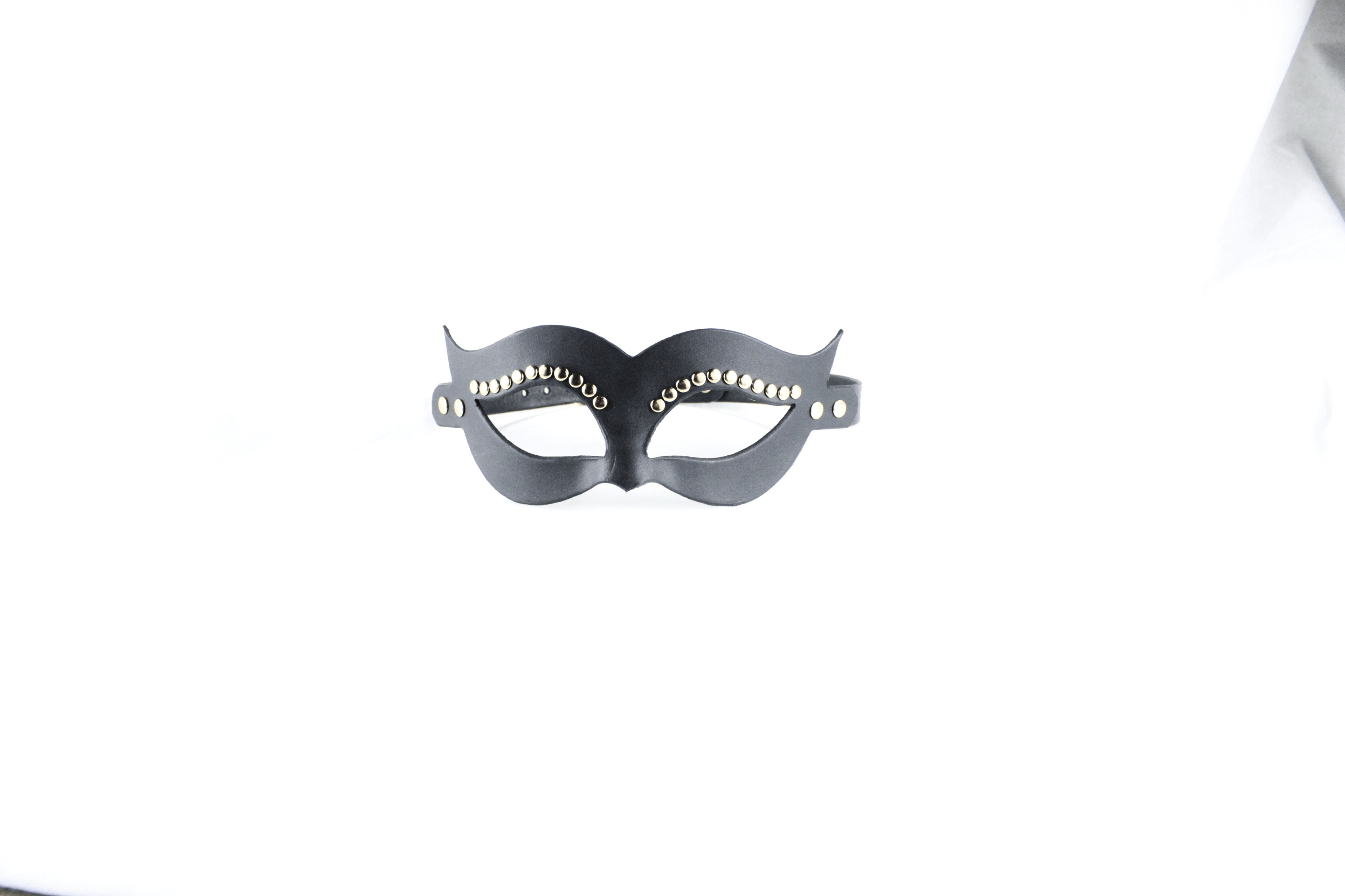 A black mask with decorative elements on it is displayed against a white background.